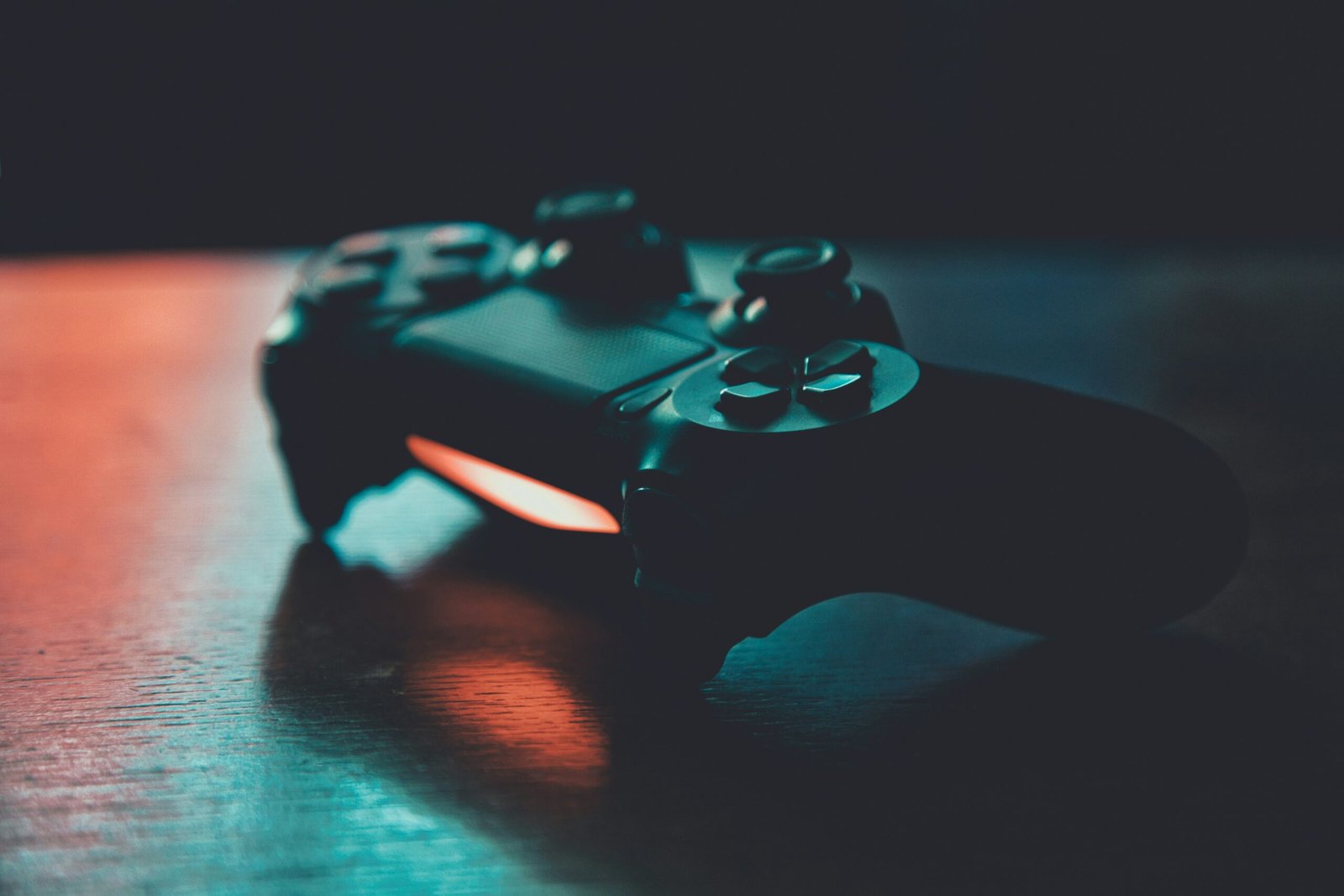 Control de videojuegos negro sobre una superficie de madera con luces azul y naranja